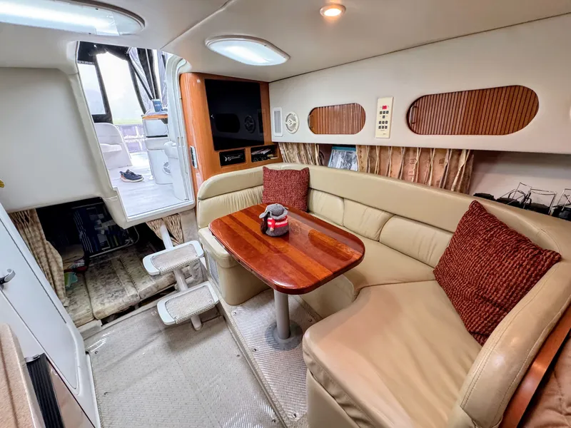 Slide: The Image of Interior of a 2001 Four Winns 298 Vista with beige sofa, wooden table, and red cushions. - 17