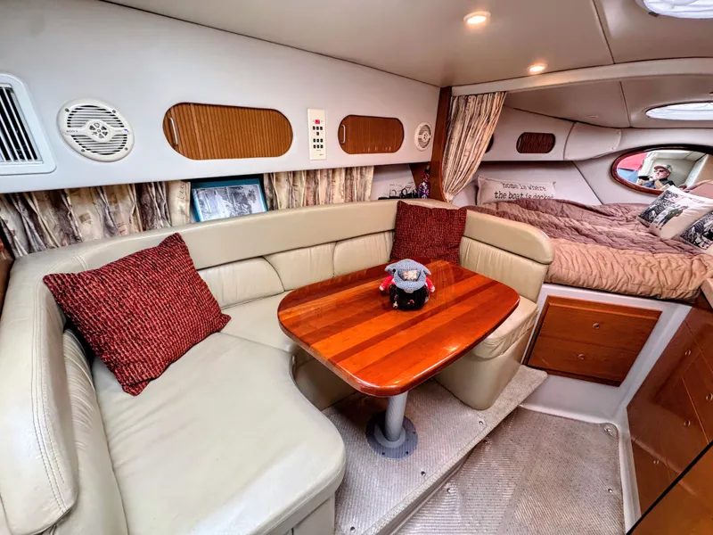Slide: The Image of Interior of a 2001 Four Winns 298 Vista with beige sofa, wooden table, and sleeping area. - 18