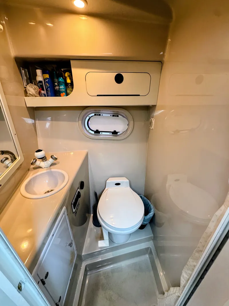 Slide: The Image of The image shows a boat bathroom with a sink, toilet, and storage space. - 25