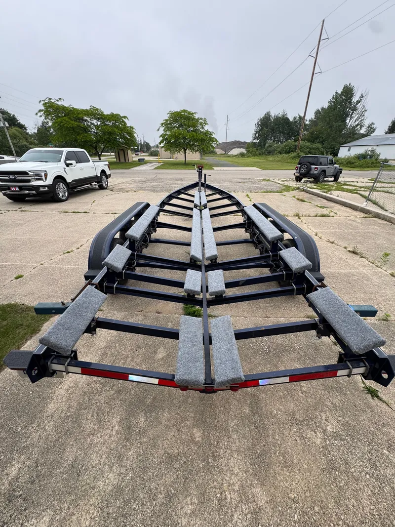 Slide: The Image of A boat trailer is parked on a lot, surrounded by vehicles and trees. - 37