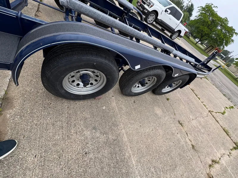 Slide: The Image of A triple-axle boat trailer is parked on a concrete surface next to a white vehicle. - 38