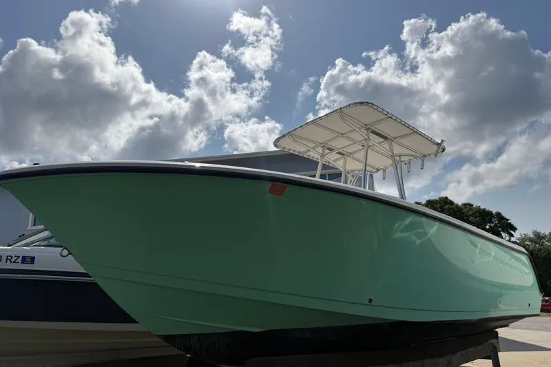 Slide: The Image of 2023 Aquasport 2200 Center Console boat under a cloudy sky, showcasing sleek design. - 2