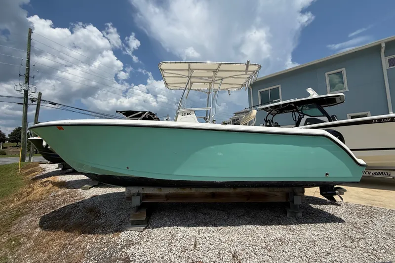 The Image of 2023 Aquasport 2200 Center Console boat with teal hull, displayed outdoors under a cloudy sky. - 0