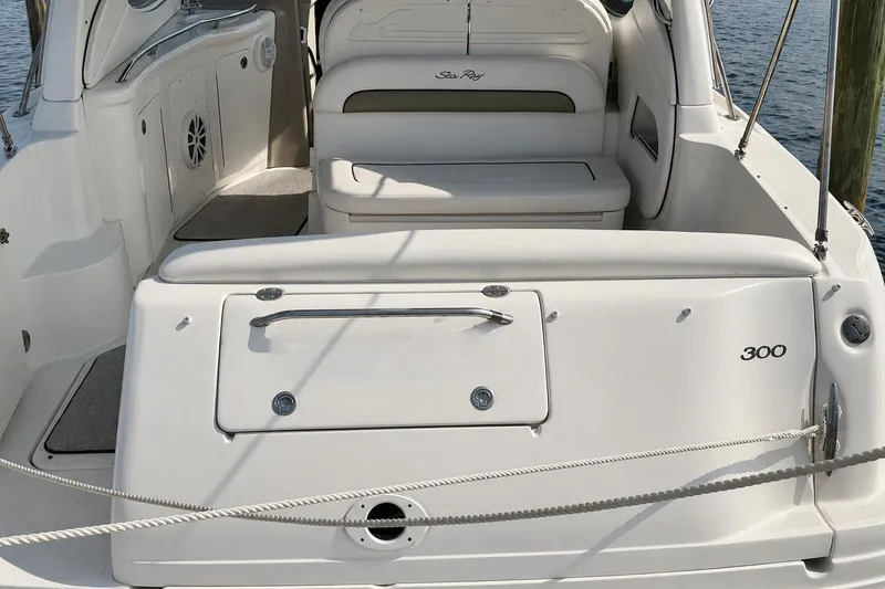 Slide: The Image of 2006 Sea Ray 300 Sundancer boat interior with seating and storage, docked by the water. - 13