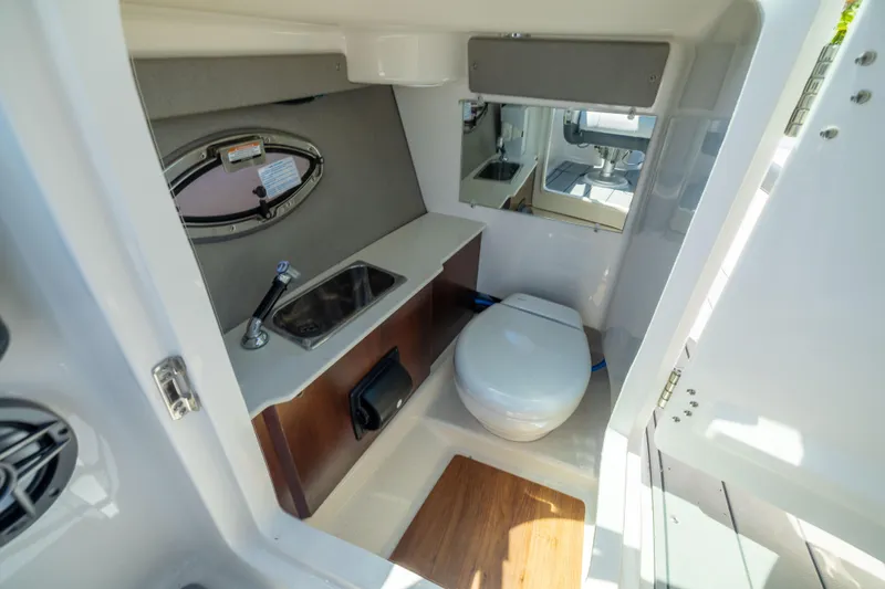 Slide: The Image of 2025 Chaparral 250 OSX boat interior with compact bathroom, featuring sink and toilet. - 12