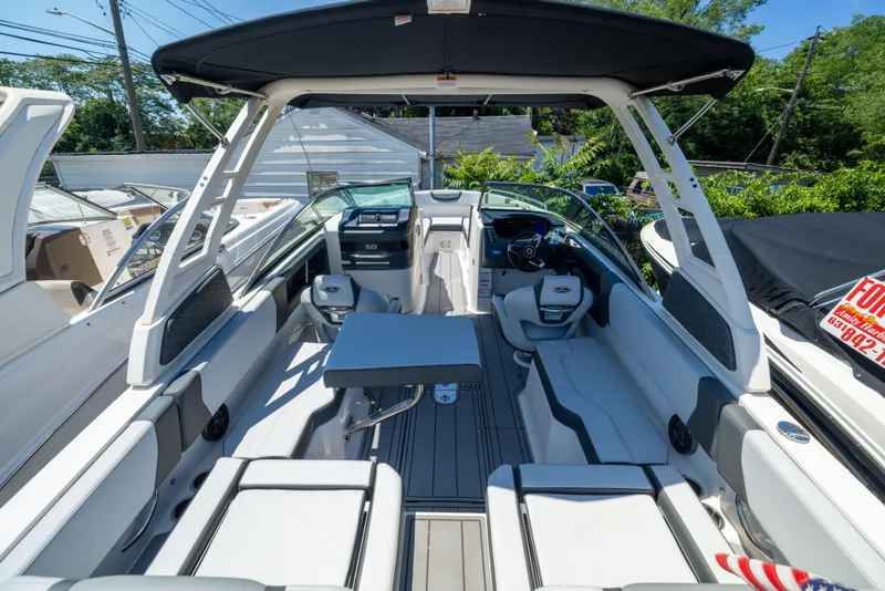 Slide: The Image of 2025 Chaparral 250 OSX boat interior with seating, table, and helm under a canopy. - 3