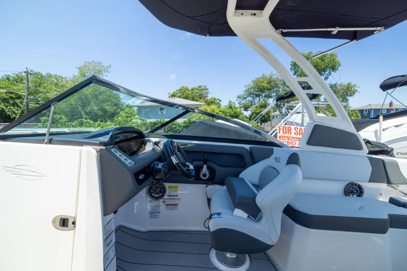 Slide: The Image of 2025 Chaparral 250 OSX boat interior with modern helm and seating, under sunny skies. - 8