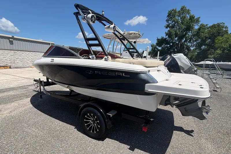 Slide: The Image of 2018 Regal 1900 ES Bowrider boat on trailer, parked outdoors under clear sky. - 1