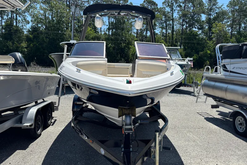 Slide: The Image of 2018 Regal 1900 ES Bowrider boat on trailer, parked outdoors, surrounded by trees. - 2