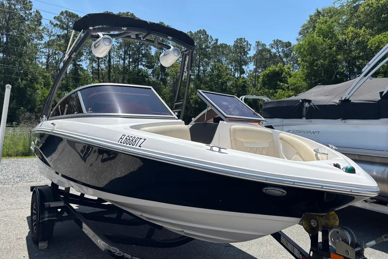 Slide: The Image of 2018 Regal 1900 ES Bowrider boat on trailer, parked outdoors, surrounded by trees. - 3