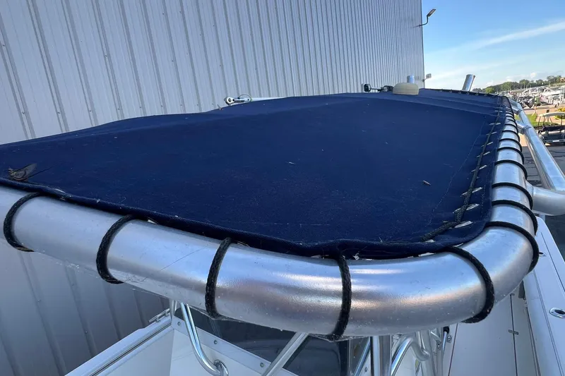 Slide: The Image of 2006 Edgewater 245CC boat with blue canvas cover and metal frame. - 14