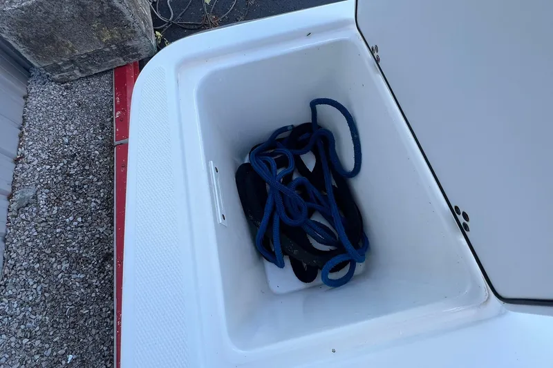 Slide: The Image of Storage compartment on a 2006 Edgewater 245CC boat with coiled blue rope inside. - 17
