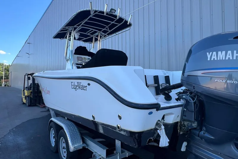 Slide: The Image of 2006 Edgewater 245CC boat with Yamaha engine on trailer, parked by a warehouse. - 31