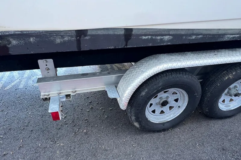 Slide: The Image of Trailer with dual wheels for 2006 Edgewater 245CC boat on asphalt surface. - 33