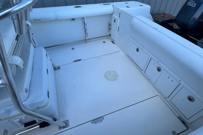 Slide: The Image of 2006 Edgewater 245CC boat interior with white seating and storage compartments. - 35