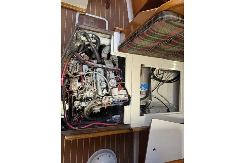 Slide: The Image of Engine compartment of a 1977 Ericson 35 sailboat, showcasing mechanical components and wiring. - 14