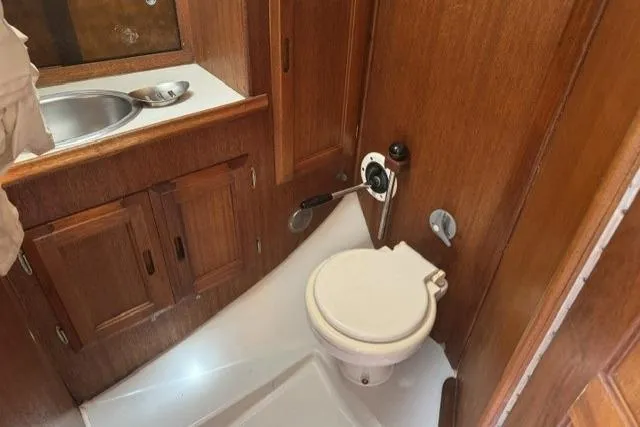 Slide: The Image of 1977 Ericson 35 yacht bathroom with wooden cabinetry and compact marine toilet. - 15