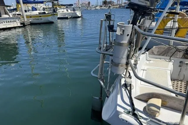 Slide: The Image of 1977 Ericson 35 sailboat docked in a marina, surrounded by calm water and other boats. - 7