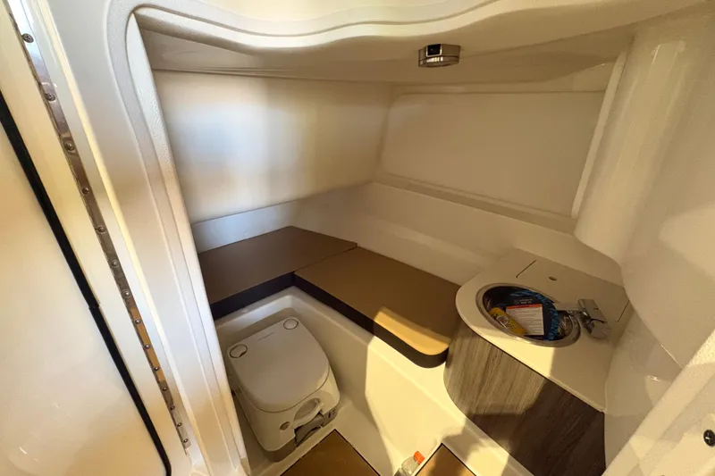 Slide: The Image of Interior of 2026 Sea Ray SDX 250 Surf boat, featuring compact bathroom amenities. - 22