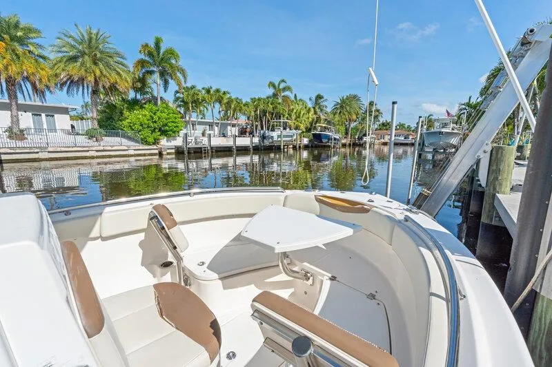 Slide: The Image of 2017 Robalo R222 Center Console boat docked by a scenic waterfront with palm trees. - 15