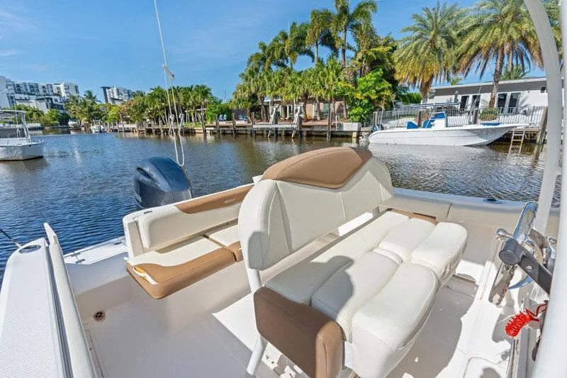 Slide: The Image of 2017 Robalo R222 Center Console boat with seating, docked by palm trees and waterfront homes. - 31