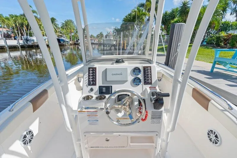 Slide: The Image of 2017 Robalo R222 Center Console boat helm with Garmin navigation, docked by a scenic canal. - 17