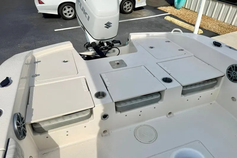 Slide: The Image of 2026 Carolina Skiff 24 Ultra Elite boat deck with Suzuki motor, storage compartments, and cup holders. - 34