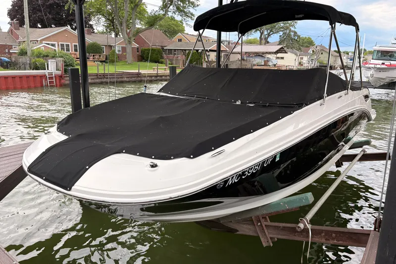 The Image of 2021 Sea Ray SDX 250 boat docked with black cover, residential background. - 2