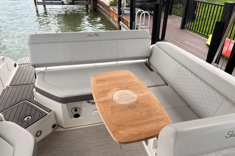 Slide: The Image of 2021 Sea Ray SDX 250 boat interior with gray seating and wooden table by the water. - 22