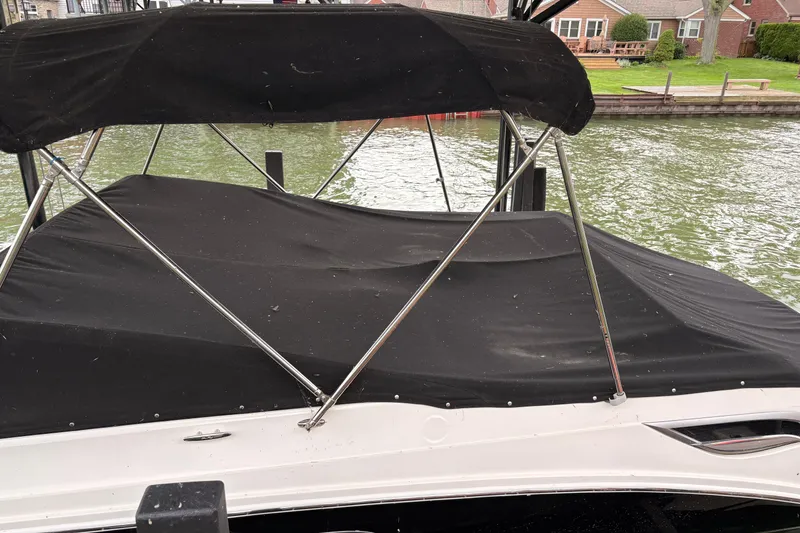 Slide: The Image of 2021 Sea Ray SDX 250 boat with black cover docked by the water. - 4