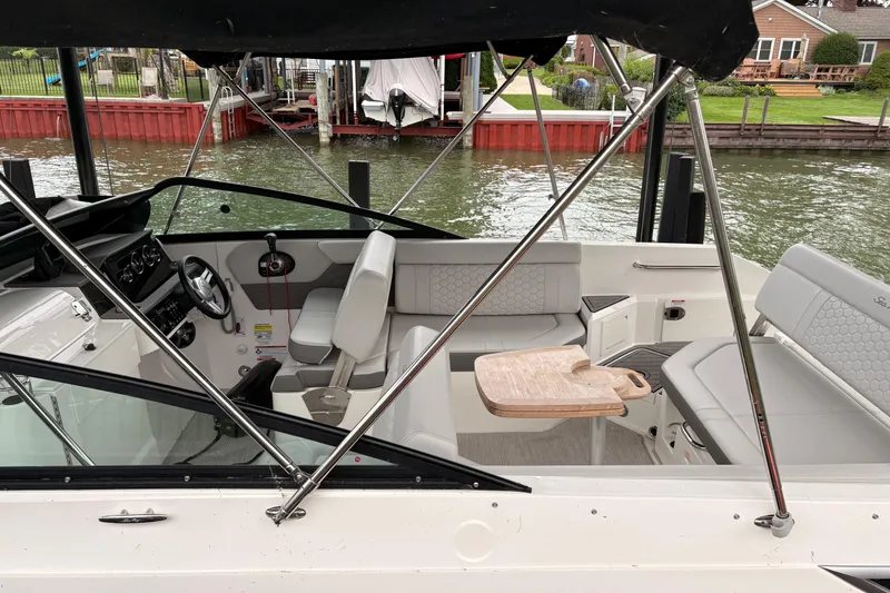 Slide: The Image of 2021 Sea Ray SDX 250 boat interior with seating and table, docked by the water. - 6
