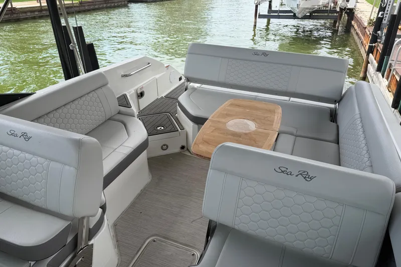 Slide: The Image of 2021 Sea Ray SDX 250 boat interior with elegant seating and wooden table by the water. - 24