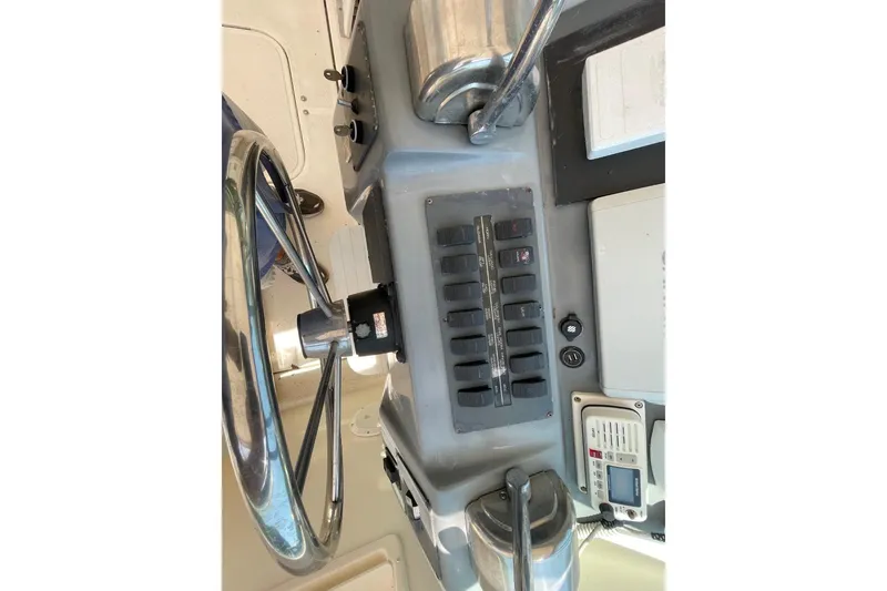 Slide: The Image of Control panel of a 1997 Tiara Yachts 3100 Open, featuring steering wheel and switches. - 15