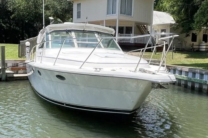 Slide: The Image of 1997 Tiara Yachts 3100 Open docked near a waterfront house. - 3