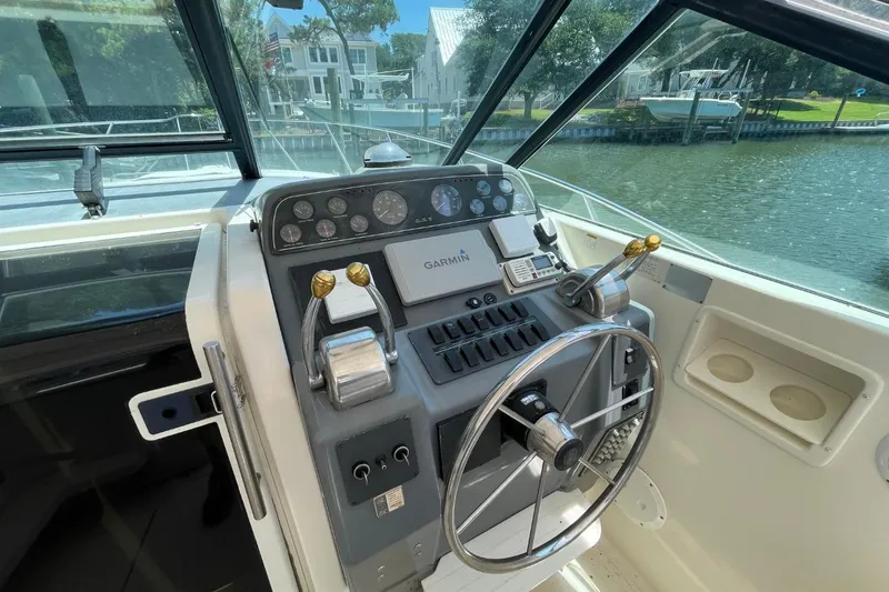Slide: The Image of 1997 Tiara Yachts 3100 Open helm with Garmin navigation, overlooking serene waterfront homes. - 9