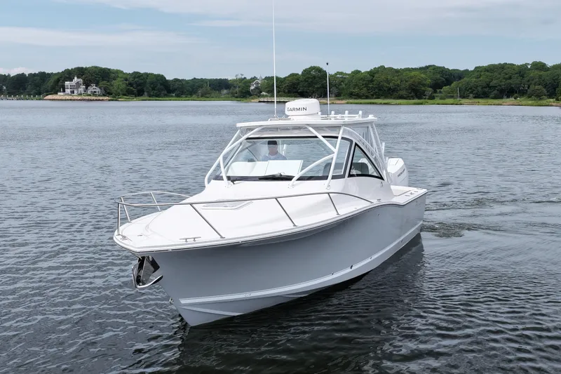 Slide: The Image of 2024 Albemarle 30 Express boat cruising on a calm lake with lush green shoreline. - 1