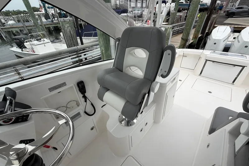Slide: The Image of 2024 Albemarle 30 Express boat interior with helm seat and steering wheel at marina. - 55
