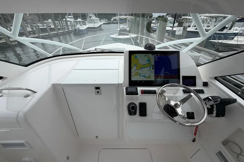 Slide: The Image of 2024 Albemarle 30 Express helm with navigation display and steering wheel at marina. - 43
