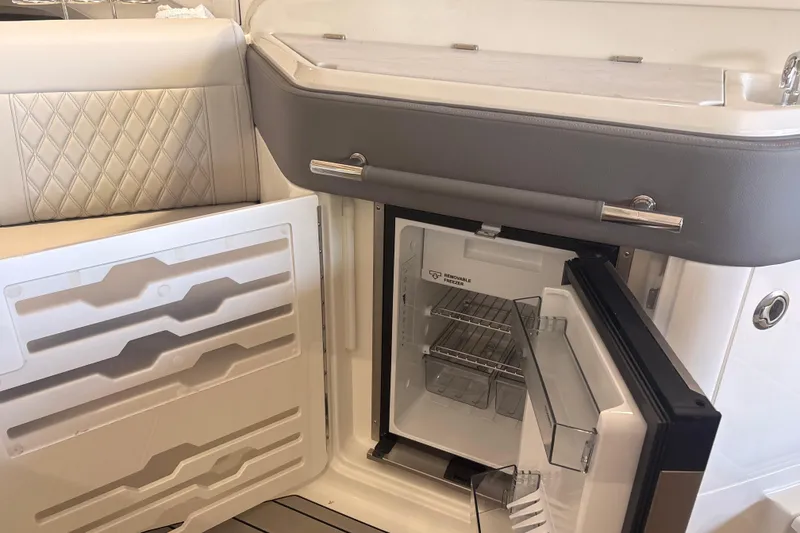 Slide: The Image of Luxurious interior of 2026 Sea Ray SLX 310 Outboard featuring a built-in mini fridge. - 16