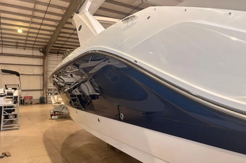 Slide: The Image of 2026 Sea Ray SLX 310 Outboard boat in a spacious indoor storage facility. - 2