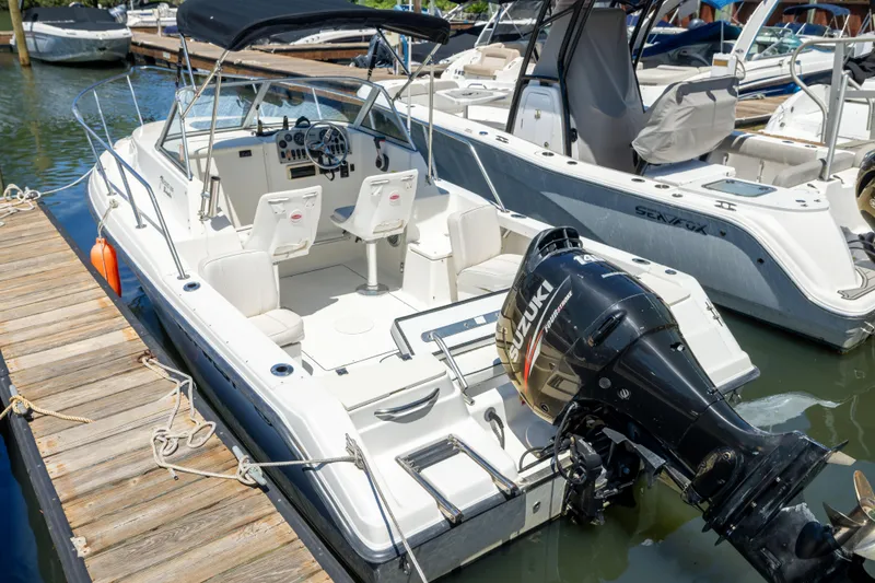 Slide: The Image of 2020 KEYWEST WA boat docked, featuring Suzuki outboard motor, spacious seating, and sleek design. - 2