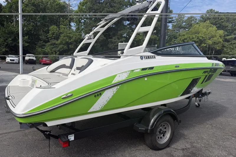 Slide: The Image of 2022 Yamaha Boats AR195 in vibrant green on a trailer, parked outdoors. - 1