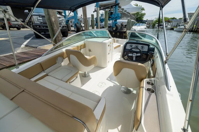 Slide: The Image of 2011 Sea Ray 220 Sundeck boat interior with beige seating and steering wheel at dock. - 25
