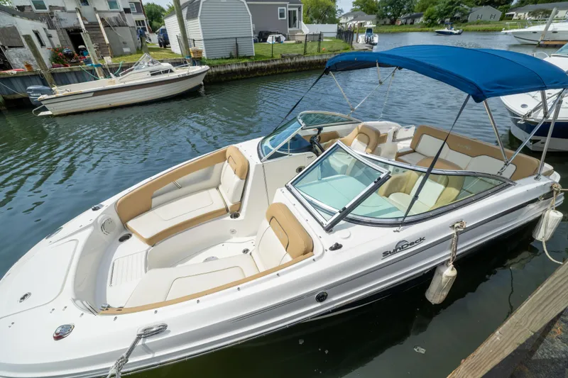 The Image of 2011 Sea Ray 220 Sundeck boat docked with blue canopy and beige seating. - 1