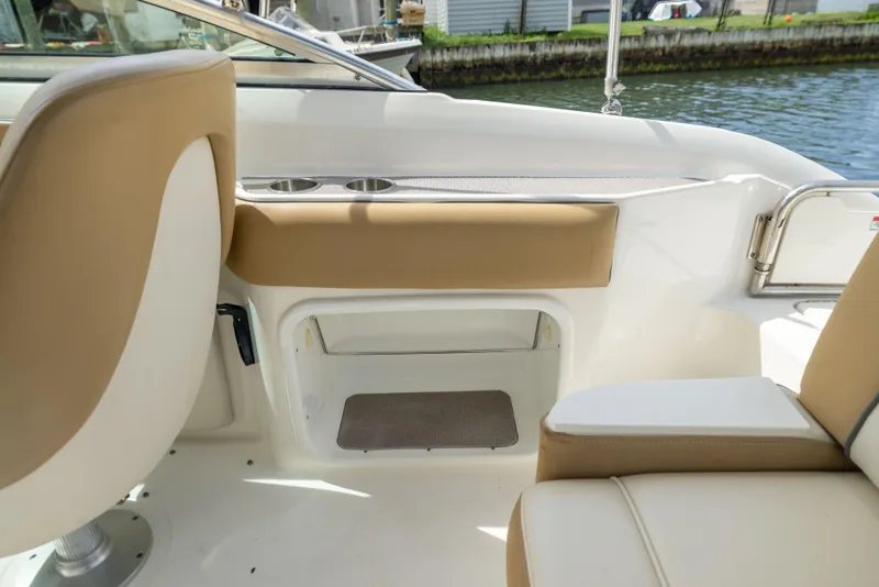 Slide: The Image of Interior of a 2011 Sea Ray 220 Sundeck boat with beige seating and cup holders. - 20
