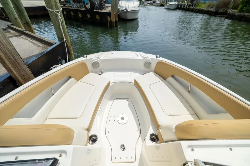 Slide: The Image of 2011 Sea Ray 220 Sundeck boat interior with beige seating, docked by the water. - 5