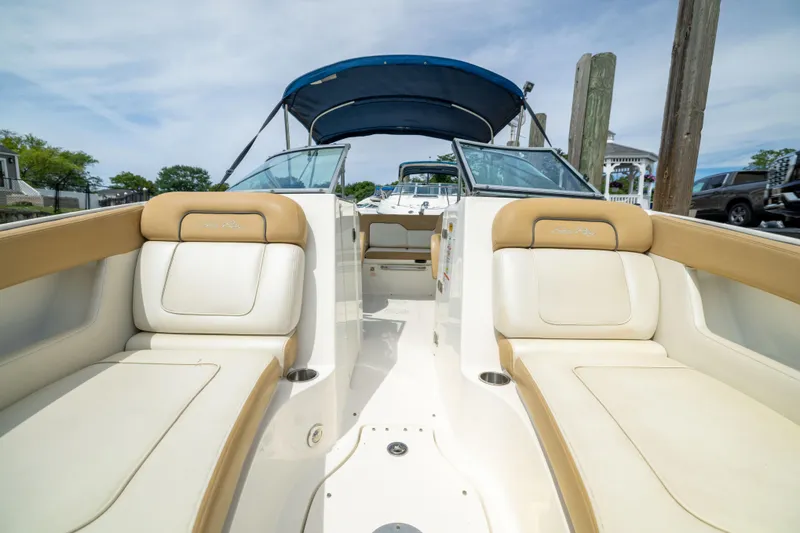 Slide: The Image of 2011 Sea Ray 220 Sundeck boat interior with tan and white seating, docked outdoors. - 7