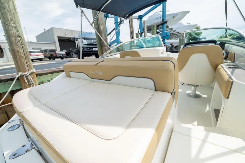 Slide: The Image of 2011 Sea Ray 220 Sundeck boat interior with beige and white seating, docked at marina. - 24