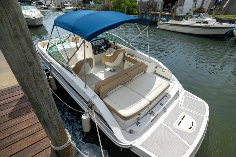 Slide: The Image of 2011 Sea Ray 220 Sundeck boat docked, featuring blue canopy and spacious seating. - 4