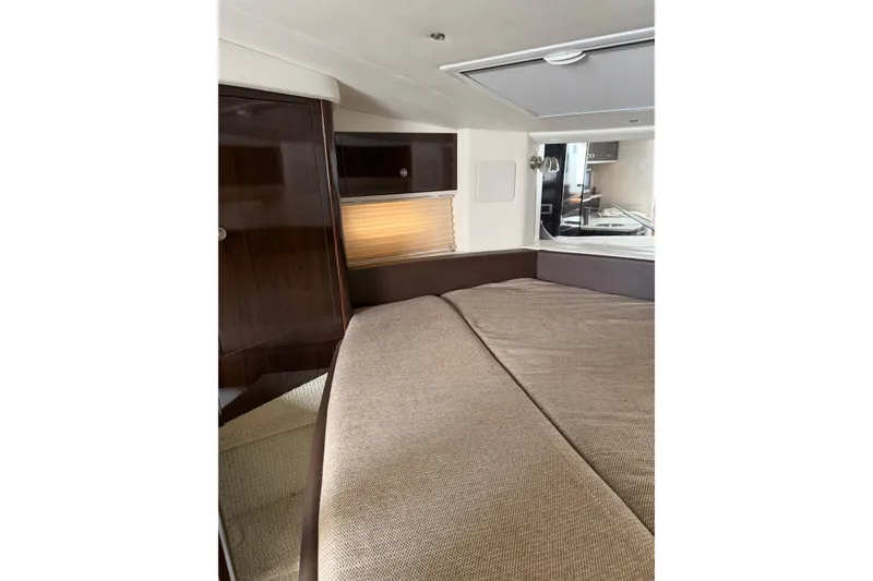 Slide: The Image of Interior cabin of 2016 Sea Ray Sundancer 330 yacht, featuring a cozy bed and elegant wood finishes. - 32